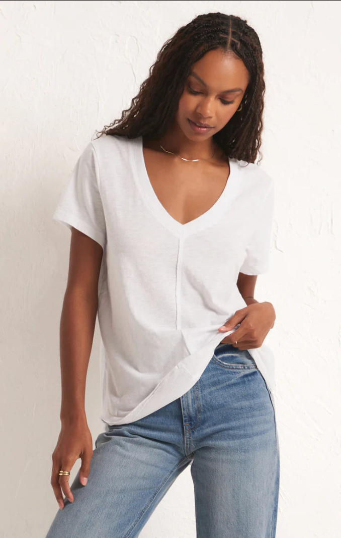 Woman wearing a white top and blue jeans on a plain background